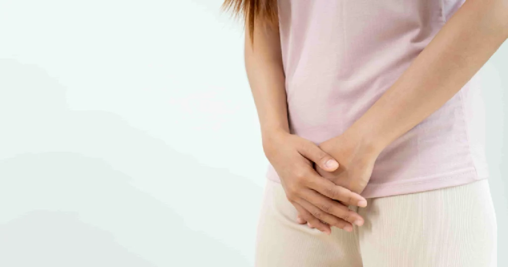 Woman in a pink shirt holding her lower abdomen due to pain during V‑Tone in Amarillo, TX.